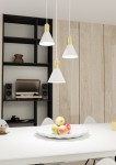 Lampa wisząca Rosa z trzema kloszami w białym kolorze i złotymi akcentami, zawieszona na cienkich przewodach. Klosze mają stożkowy kształt. Produkt umieszczony nad białym stołem z misą owoców, w tle czarna półka i sprzęt audio.