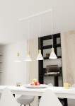 Lampa wisząca Rosa z czterema kloszami w kolorze białym z złotymi akcentami, zawieszona na białych przewodach. Widoczna na tle jasnej ściany i czarnej półki. Ułożona nad białym stołem z owocami w misce.