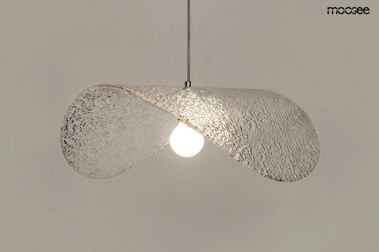Lampa wisząca Capello FI 80 w kolorze chromu i transparentnym, z falującym kloszem wykonanym z przezroczystego materiału, z widoczną żarówką E27. Ujęcie z dołu, pokazujące detal i fakturę klosza.