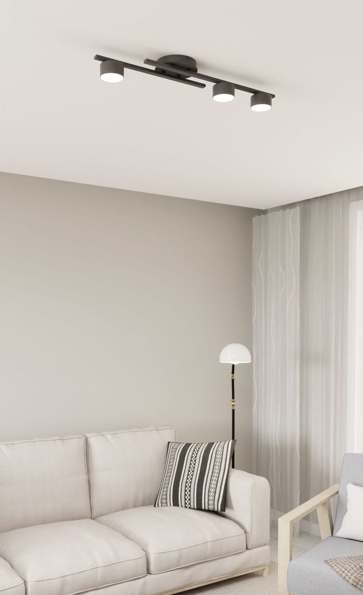 Czarna lampa sufitowa z trzema oprawami GX53, zamontowana na suficie, widoczna z dołu. Prosta konstrukcja z metalowymi kloszami, idealna do nowoczesnych wnętrz, w otoczeniu jasnej kanapy i lampy stojącej.