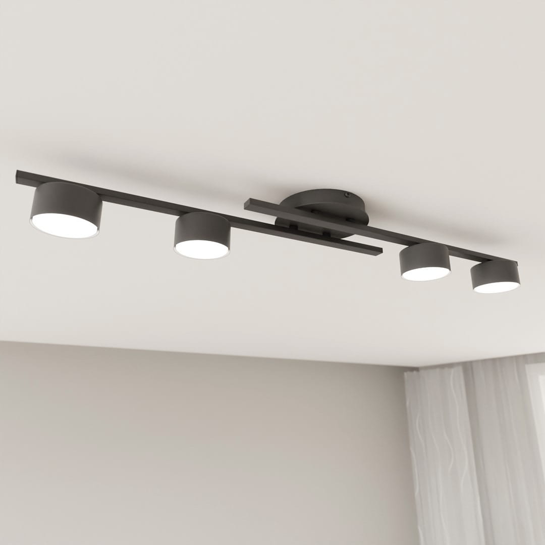 Czarna lampa sufitowa z czterema okrągłymi oprawami na żarówki GX53, zamontowana na prostokątnej belce. Ujęcie z dołu, ukazujące równomierne rozmieszczenie źródeł światła na gładkim suficie. Tło w jasnym kolorze.