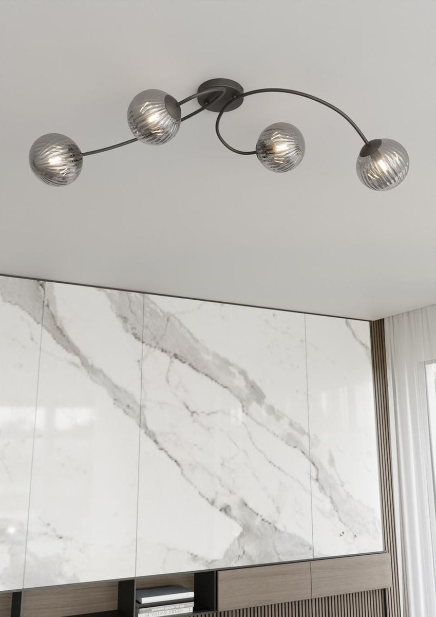 Czarna lampa sufitowa Vibra z czterema kloszami E14 w kształcie okrągłych, szklanych kul. Klosze mają prążkowaną fakturę i są zawieszone na delikatnych, zakrzywionych ramionach. Lampa zamontowana na białym suficie, w tle widoczna jasna, marmurowa ściana.