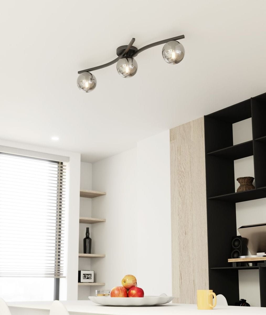 Lampa sufitowa Opus z trzema kulistymi kloszami w kolorze czarnym i grafitowym, zamontowana na prostym, metalowym stelażu. Klosze mają lustrzaną powierzchnię, co odbija światło. Zawieszona pod sufitem w nowoczesnym wnętrzu, nad stołem z owocami.