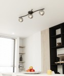 Lampa sufitowa Opus z trzema kulistymi kloszami w kolorze czarnym i grafitowym, zamontowana na prostym, metalowym stelażu. Klosze mają lustrzaną powierzchnię, co odbija światło. Zawieszona pod sufitem w nowoczesnym wnętrzu, nad stołem z owocami.