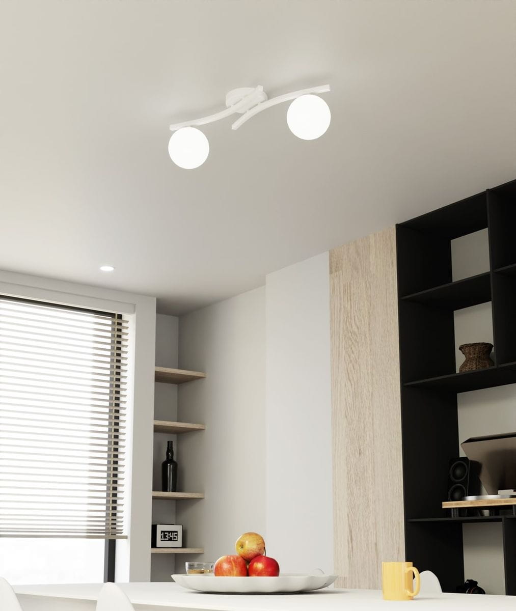 Lampa sufitowa Opus z dwoma opalowymi kloszami E14, zamontowana na białej podstawie. Ujęcie z dołu, ukazujące nowoczesny design i sposób oświetlenia wnętrza. W tle widać jasny stół z owocami oraz regały.