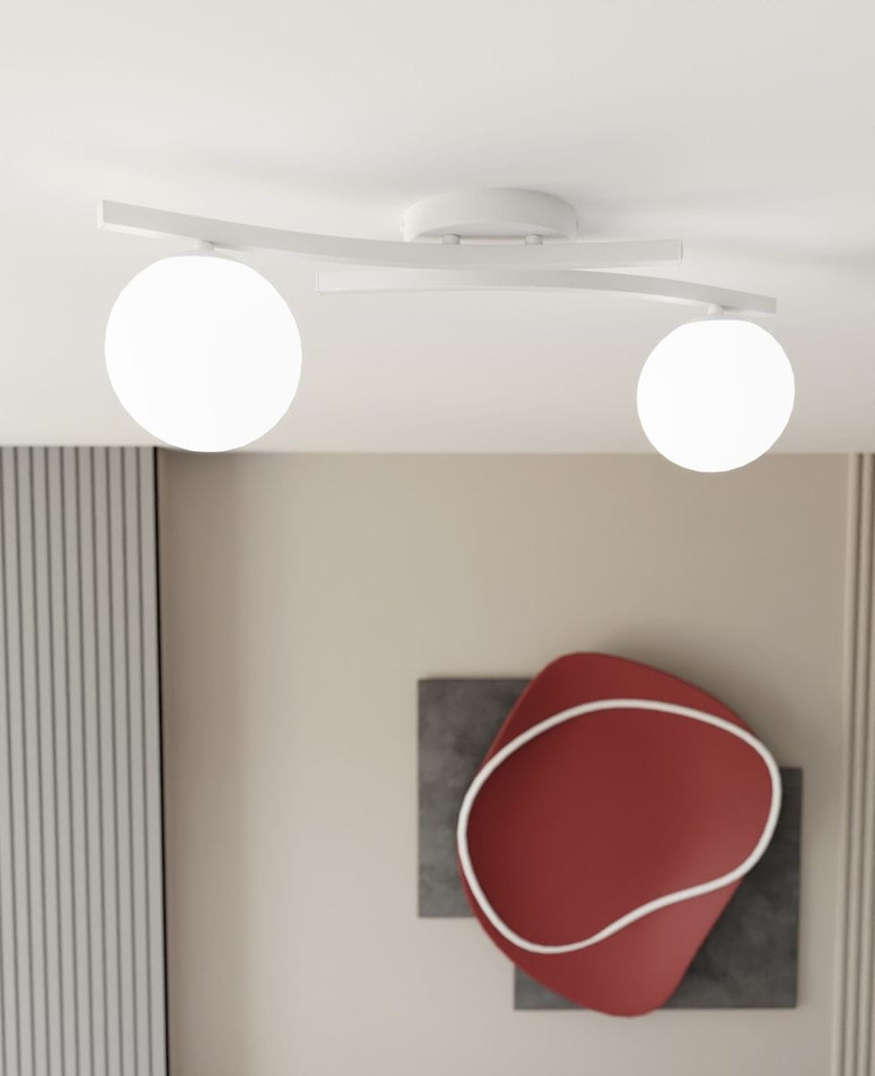 Lampa sufitowa Opus z dwoma opalowymi kulami na białej, zakrzywionej podstawie. Ujęcie z dołu, ukazujące równomierne rozmieszczenie źródeł światła oraz minimalistyczny design. Tło w neutralnych kolorach z dekoracją w odcieniu czerwonym.