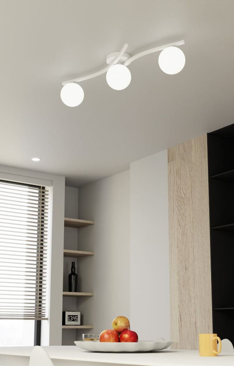 Lampa sufitowa Opus z trzema kulistymi kloszami w kolorze opalowym, zamontowana na białej, zakrzywionej konstrukcji. Ujęcie z dołu, pokazujące lampę w nowoczesnym wnętrzu z widocznymi półkami i dekoracjami.