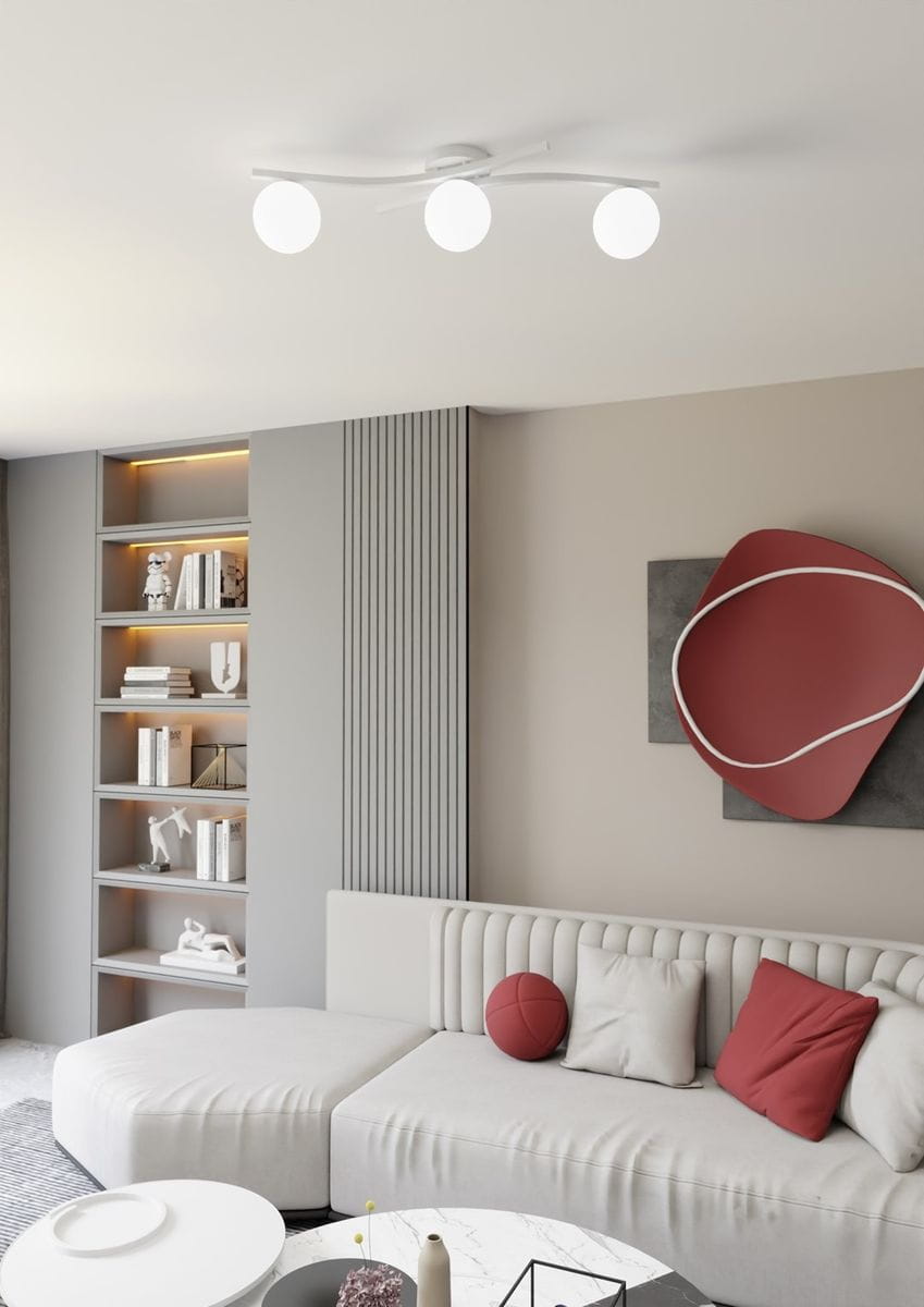 Lampa sufitowa Opus w kolorze białym z trzema opalowymi kloszami na żarówki E14. Zawieszona na gładkim, okrągłym mocowaniu, w nowoczesnym stylu. Widoczna w aranżacji wnętrza z jasną sofą i regałem.