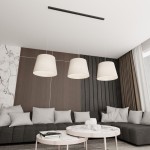 Lampa wisząca Epoca z trzema kloszami w kolorze beżowym zawieszona na czarnej listwie. Klosze mają stożkowaty kształt i są wykonane z materiału. Lampa zainstalowana w nowoczesnym wnętrzu z szaro-beżową sofą i okrągłym stołem kawowym.