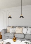 Lampa wisząca Seco 1xE27 w kolorze czarnym z jasnym drewnem, zawieszona na czarnym przewodzie. Okrągła, metalowa czasza z drewnianym elementem u góry. W tle szary narożnik z poduszkami i stół kawowy z dekoracjami.
