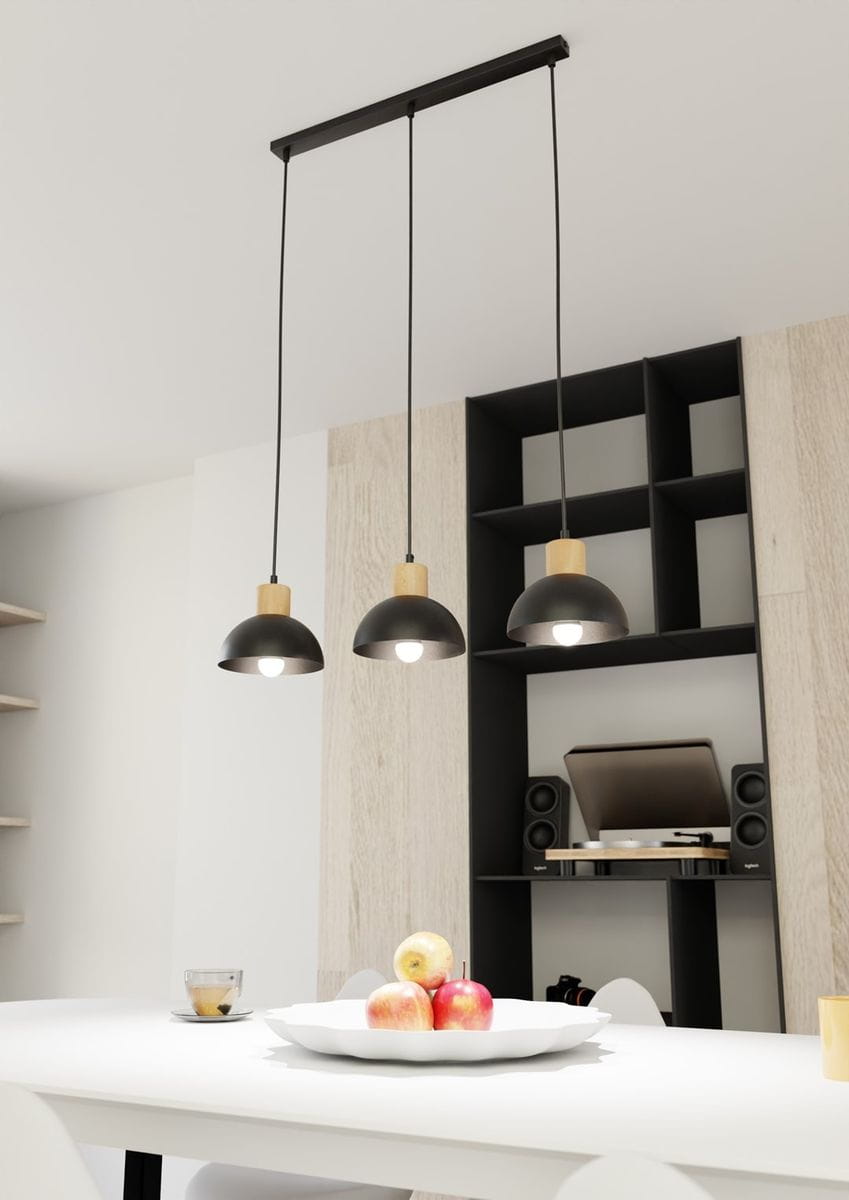 Lampa wisząca Seco z trzema źródłami światła E27, z czarnymi kloszami i jasnymi drewnianymi detalami. Ujęcie z dołu, pokazujące lampę nad stołem, w otoczeniu białego talerza z owocami oraz sprzętu audio w tle.