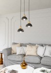 Lampa wisząca Seco 3xE27 w kolorze czarnym z jasnym drewnem. Trzy klosze w kształcie półkul, zawieszone na czarnych przewodach, z widocznymi źródłami światła. Produkt umieszczony w nowoczesnym wnętrzu z szarym sofą i dekoracjami na stole.