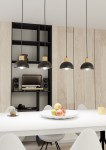 Lampa wisząca Seco 4xE27 w kolorze czarnym z jasnymi drewnianymi elementami, zawieszona na długich kablach. Widoczna w aranżacji jadalni nad białym stołem z owocami. Tło to jasne drewniane panele oraz czarna, minimalistyczna półka.