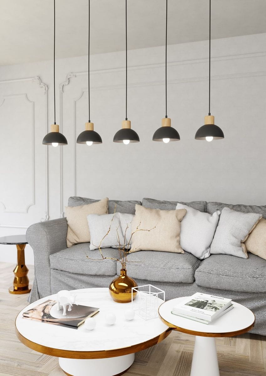 Lampa wisząca Seco 5xE27 w kolorze czarnym z jasnym drewnem. Posiada pięć kloszy w kształcie półkul, zawieszonych na długich, czarnych przewodach. Lampa umieszczona nad szarym narożnikiem z poduszkami, w nowoczesnym wnętrzu.
