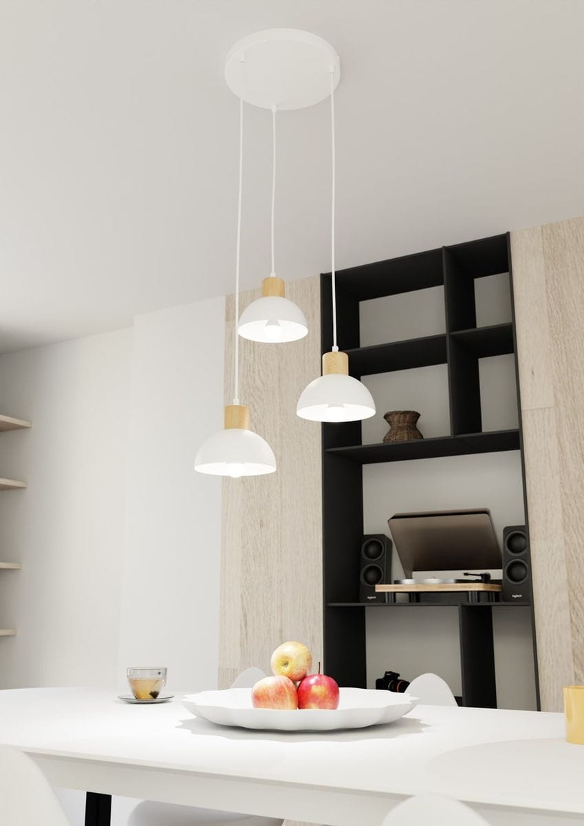 Lampa wisząca Seco z trzema kloszami, wykonana z białego metalu i jasnego drewna. Klosze mają zaokrąglony kształt, zawieszone na białych przewodach. Lampa umieszczona nad białym stołem z owocami, w tle czarna półka i sprzęt audio.