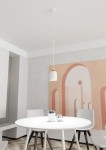 Lampa wisząca Target 1xE27 w kolorze białym z złotym wykończeniem, zawieszona na białym przewodzie, umieszczona nad okrągłym białym stołem. Tło stanowi jasna ściana z dekoracyjnym muralem w odcieniach różu i beżu.