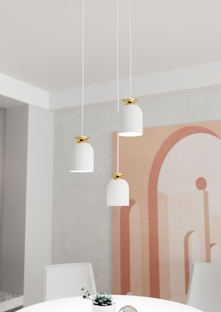 Lampa wisząca Target 3xE27 w kolorze białym z elementami złotymi, zawieszona na białych przewodach. Trzy klosze w kształcie dzwonu z złotymi mocowaniami, umieszczone nad okrągłym białym stołem, w minimalistycznym wnętrzu z pastelowym tłem.