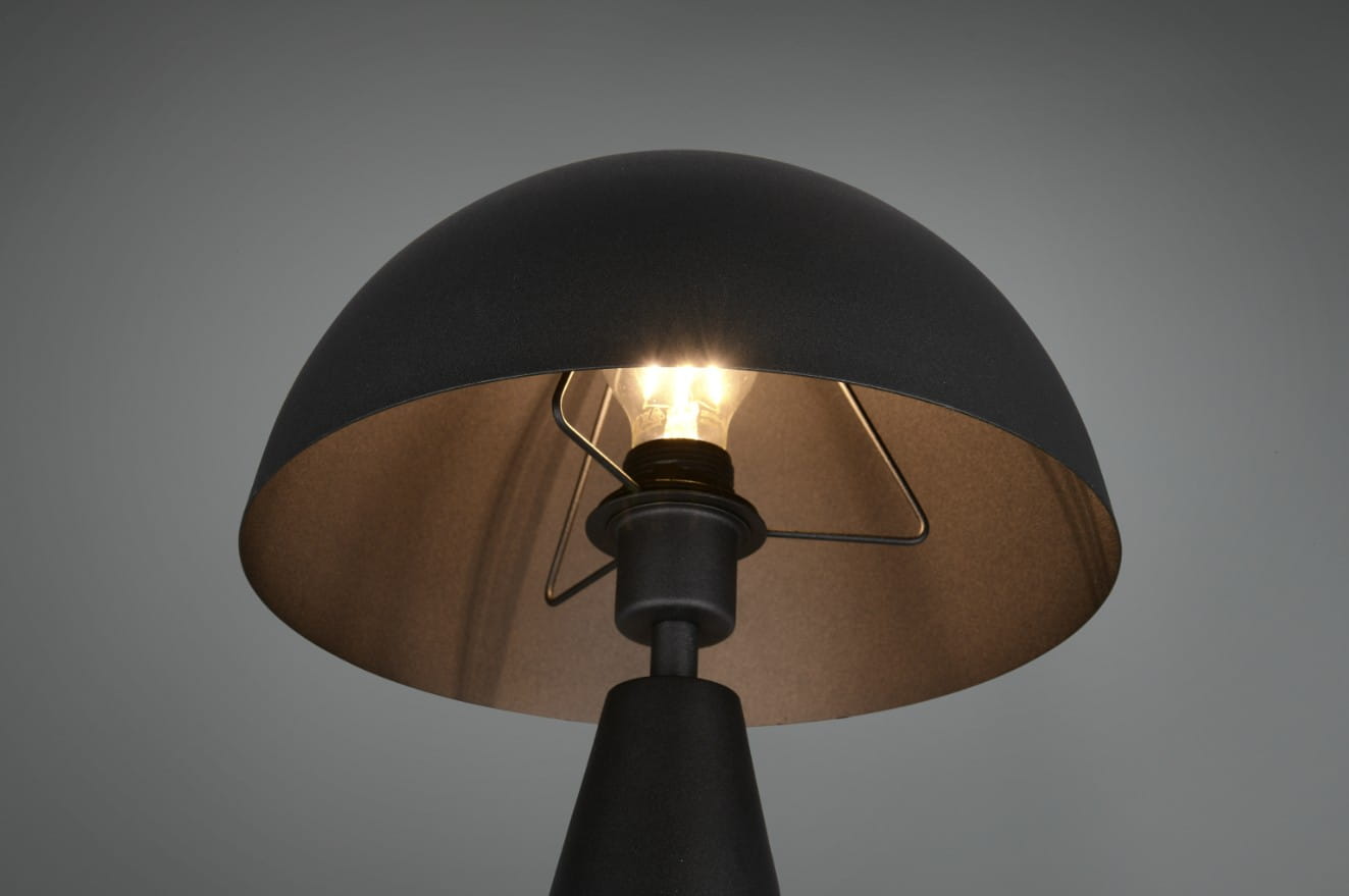 Lampa stołowa Alfie z jedną oprawą E27 w czarnym kolorze. Okrągły klosz z matowego metalu z wewnętrzną złotą powłoką, z widoczną żarówką i metalowym mocowaniem. Ujęcie z góry, pokazujące detal klosza i źródła światła.