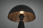Lampa stołowa Alfie z jedną oprawą E27 w czarnym kolorze. Okrągły klosz z matowego metalu z wewnętrzną złotą powłoką, z widoczną żarówką i metalowym mocowaniem. Ujęcie z góry, pokazujące detal klosza i źródła światła.
