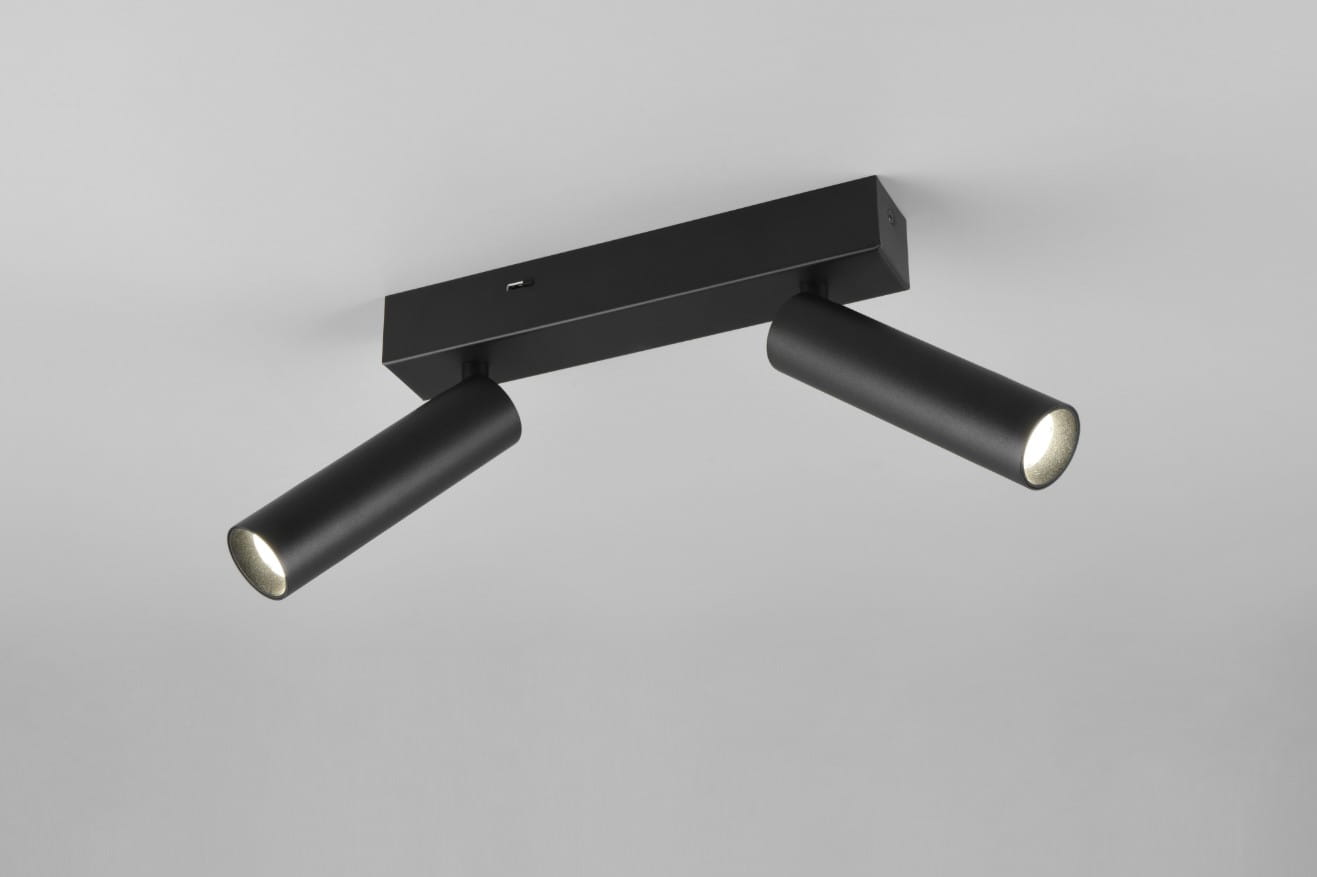 Czarna lampa sufitowa typu spot, składająca się z dwóch cylindrycznych źródeł światła LED o mocy 11W, zamontowanych na prostokątnej podstawie. Ujęcie frontalne, widoczna matowa faktura i minimalistyczny design.