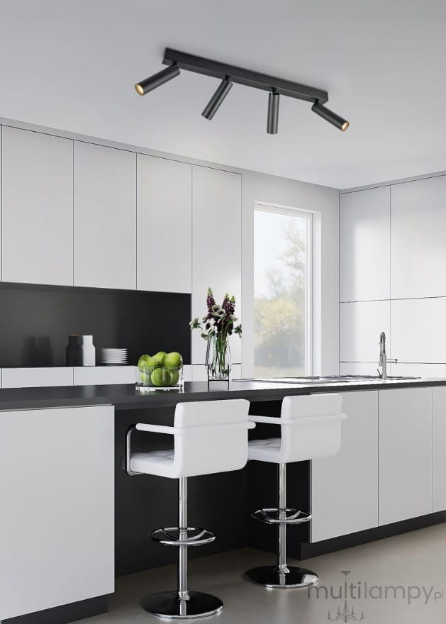 Lampa sufitowa Ambala w kolorze czarnym z czterema ruchomymi punktami LED, zamontowana na suficie. Produkt znajduje się w nowoczesnej kuchni z białymi i czarnymi szafkami oraz barowymi krzesłami. W tle widoczny stół z owocami i kwiatami.