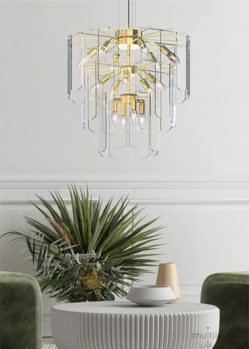 Lampa wisząca Nira 14xE14 w kolorze złotym, z przezroczystymi elementami. Ujęcie frontalne, lampa zawieszona nad okrągłym stołem. W tle rośliny dekoracyjne oraz zielone krzesła. Wysoka jakość wykonania, nowoczesny design.