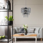 Lampa wisząca Nira w kolorze czarnym z chromowanymi detalami, z 14 miejscami na żarówki E14. Zawieszona nad jasną sofą w aranżacji salonu, z widocznymi elementami dekoracyjnymi. Szklane elementy lampy tworzą nowoczesny wygląd.