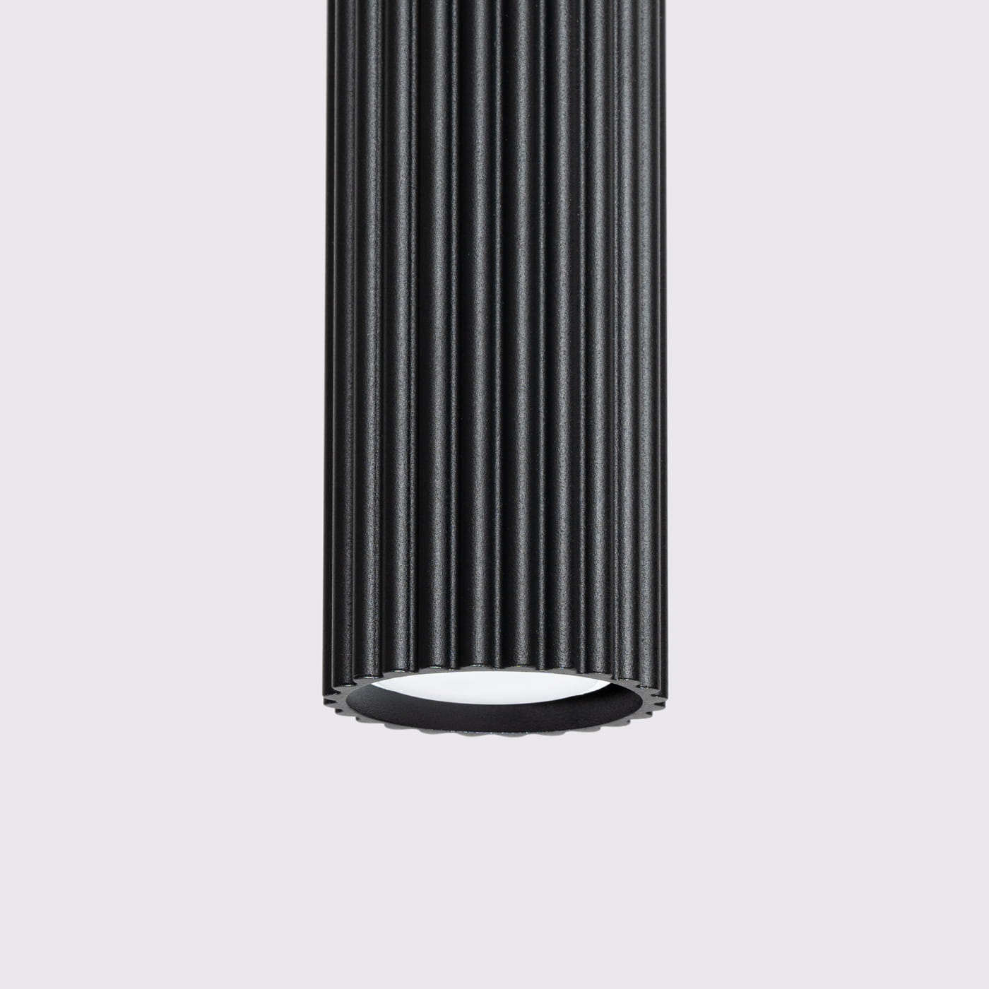 Lampa wisząca Karbon 2 w kolorze czarnym z dwoma gniazdami GU10. Posiada cylindryczny kształt z wyraźnym, poziomym żłobieniem. Widać dolną część lampy z białym kloszem, na prostym, jasnym tle.