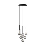 Lampa wisząca Arcturus z siedmioma źródłami światła G9, w kolorze czarnym i złotym. Okrągłe klosze w szklanym wykończeniu zawieszone na różnych wysokościach, z cienkimi, czarnymi przewodami. Montowana na okrągłej podstawie sufitowej.