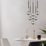 Lampa wisząca Arcturus z siedmioma kloszami G9 w kolorze czarnym i złotym. Klosze mają kulisty kształt i są zawieszone na długich, cienkich linkach. Produkt umieszczony nad okrągłym stołem w minimalistycznym wnętrzu.