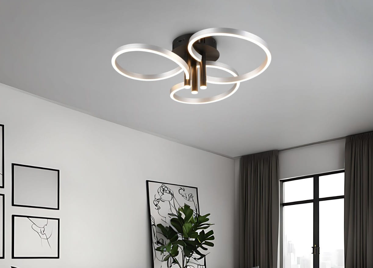 Czarna lampa sufitowa Caruso z aluminiowymi okręgami, z trzema źródłami światła LED. Ujęcie z dołu, ukazujące nowoczesny design z płaskim montażem do sufitu. Tło stanowi minimalistyczne wnętrze z roślinnością i obrazami na ścianie.
