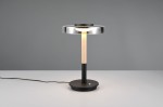 Lampa stołowa Celeste z czarną podstawą i przydymionym kloszem. Posiada drewniany trzon oraz okrągłą podstawę. Ujęcie frontalne, produkt stoi na jasnym stole, z widocznym kablem zasilającym.