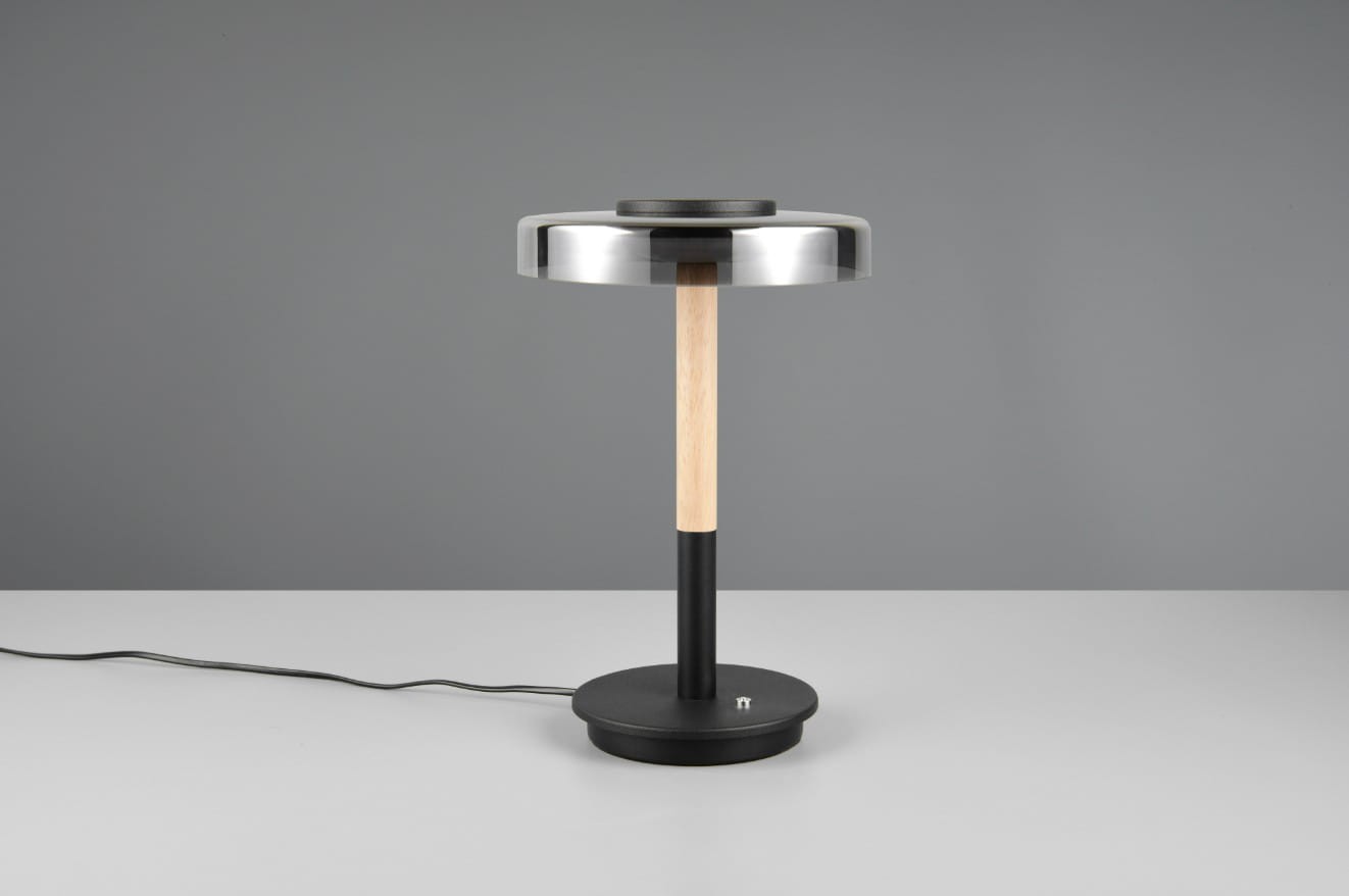 Lampa stołowa Celeste z 1xLED/10W, czarna podstawa okrągła, drewniany trzon, metalowa klosz w kolorze przydymionym. Ujęcie frontalne, stojąca na jednolitym tle, widoczny kabel zasilający.