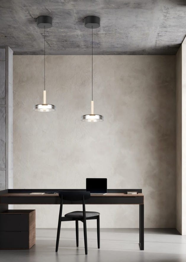 Lampa wisząca Celeste w kolorze czarnym i chromowym z jedną diodą LED 10W. Zawieszona na cienkim kablu, z okrągłym kloszem i drewnianym detalem, umieszczona nad biurkiem w minimalistycznym wnętrzu.