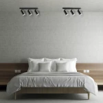 Czarna lampa sufitowa Turyn IP44 z trzema reflektorami GU10, zamontowana na suficie, skierowana w dół. W tle widoczna nowoczesna sypialnia z łóżkiem i poduszkami w jasnych odcieniach.