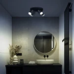 Czarna lampa sufitowa Turyn IP44 z czterema reflektorami GU10, zamontowana na suficie w nowoczesnej łazience. W tle widoczna okrągła lustro, umywalka oraz dekoracje, na przykład suszone kwiaty i figurka.