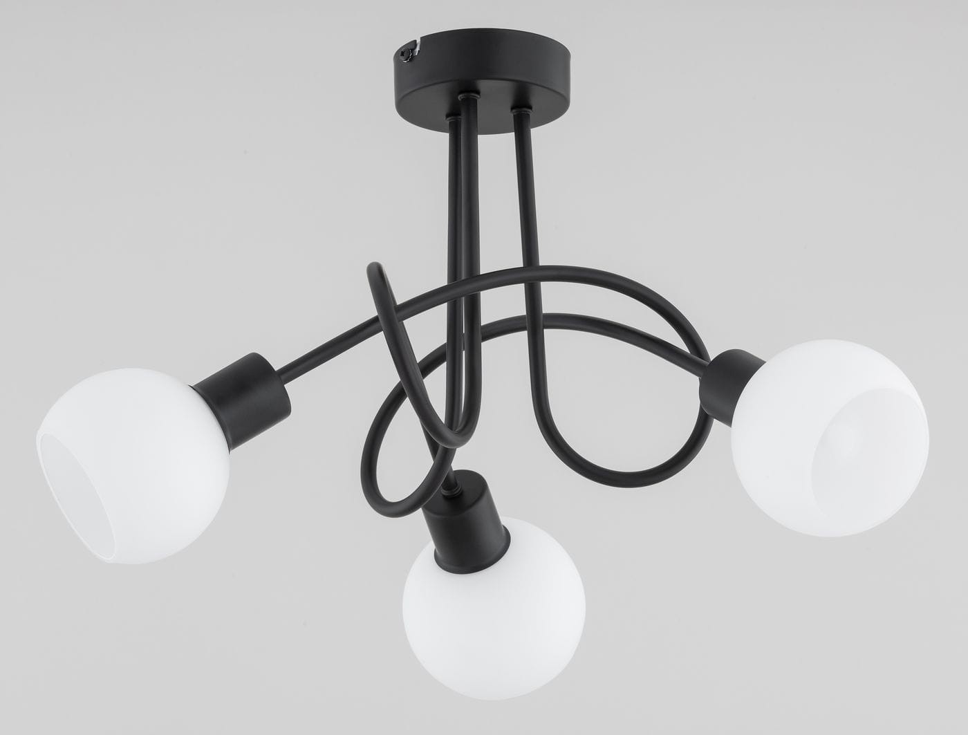 Czarna lampa wisząca Eryka Black z trzema oprawami E14. Posiada okrągłe, matowe klosze w białym kolorze, zamocowane na elastycznych, czarnych ramionach. Ujęcie z góry, ukazujące kształt i układ elementów.