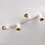 Lampa sufitowa Arras w kolorze białym z złotymi detalami, z czterema punktami świetlnymi GU10. Ułożona poziomo, z widocznymi teksturowanymi uchwytami i okrągłymi kloszami, na jednolitym tle. Idealna do nowoczesnych wnętrz.