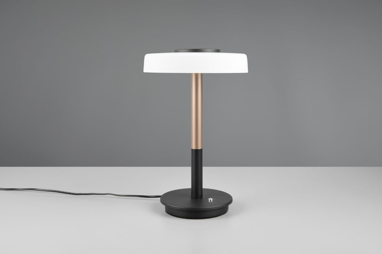 Lampa stołowa Celeste z białym kloszem i metalowym stelażem w kolorze kawowym, z okrągłą podstawą w czerni. Ujęcie frontalne, produkt leży na stole, widoczny kabel zasilający. Idealna do nowoczesnych wnętrz.