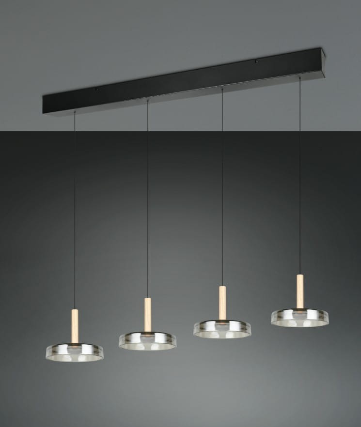 Lampa wisząca Celeste z czterema kloszami LED, w kolorze czarnym z chromowanymi detalami. Klosze mają okrągły kształt i drewniane uchwyty. Zawieszona na cienkich linkach, umieszczona na prostokątnej, czarnej podstawie.