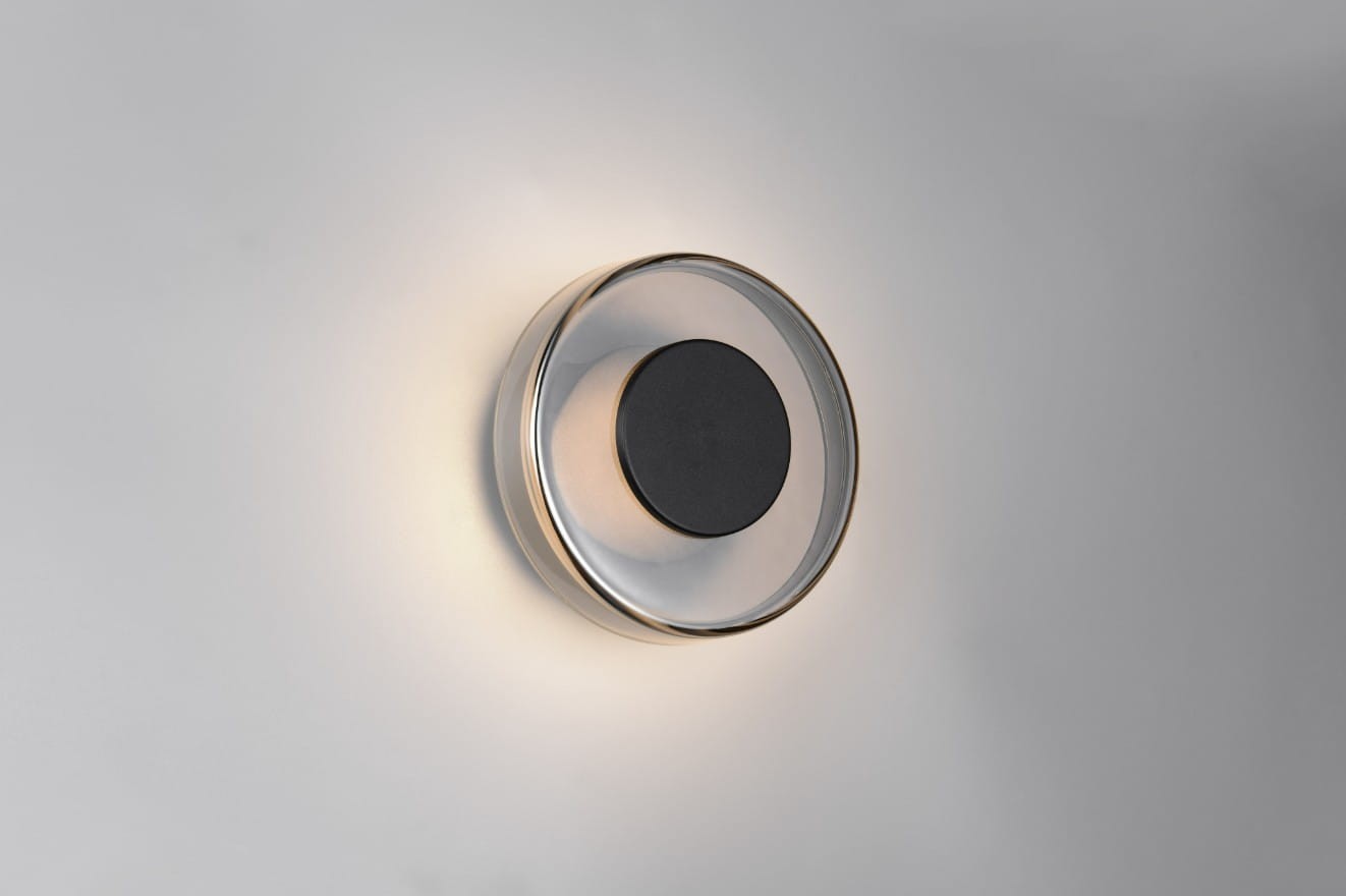 Plafon Celeste 1xLED/10W w kolorze czarnym i chromowanym, okrągły, z centralnym czarnym elementem. Zainstalowany na ścianie, emitujący subtelne światło. Wykonany z przezroczystego materiału, z delikatnym wykończeniem.