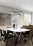 Lampa wisząca Darvin z czarnym wykończeniem, zawieszona nad białym, owalnym stołem w jadalni. Posiada trzy okręgi z podświetleniem LED. W tle widoczna ściana z obrazem i okno, a obok stół z krzesłami oraz dekoracyjne naczynia.