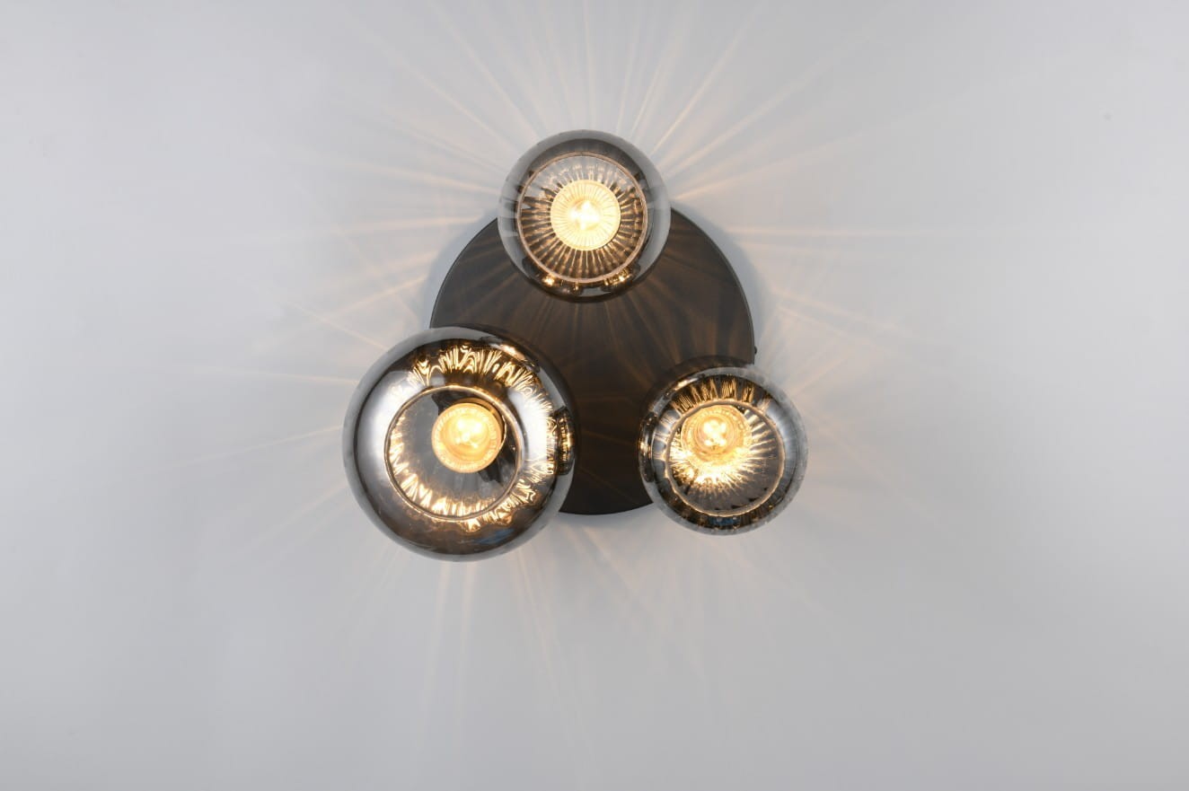 Lampa sufitowa Diva 3xE27 w kolorze czarnym i chromowanym, z trzema okrągłymi kloszami. Montowana pod sufitem, widoczne źródła światła emitujące promienie. Klosze mają refleksyjne wykończenie, a całość jest umieszczona na okrągłej podstawie.