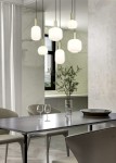 Lampa wisząca Diva z sześcioma oprawami E27 w czarno-białym kolorze, zawieszona na cienkich linkach. Szklane klosze o różnych kształtach, w nowoczesnym wnętrzu z drewnianym stołem i metalowymi krzesłami. Tło z marmurowymi ścianami.