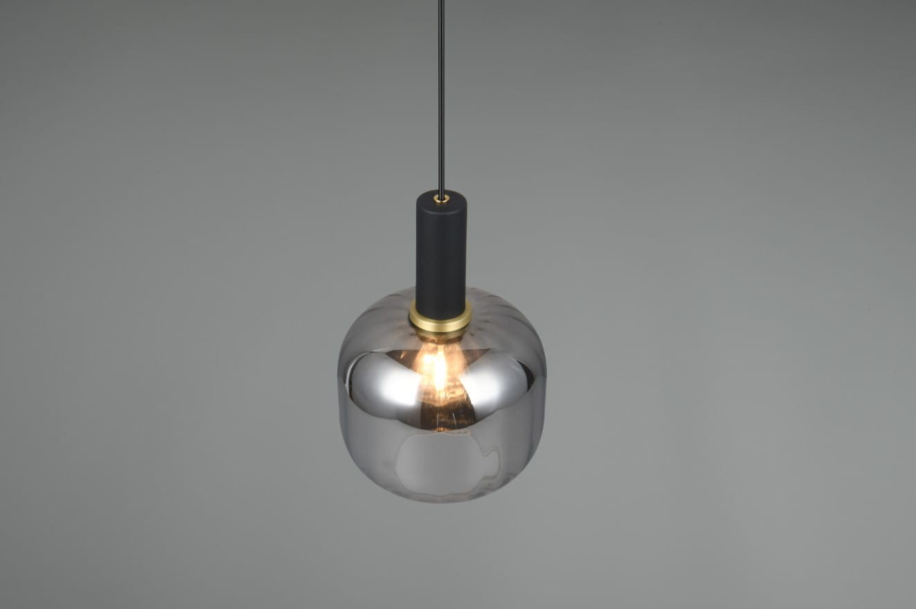 Lampa wisząca Diva z oprawą w kolorze czarnym i chromowanym, z żarówką E27. Okrągła, metaliczna czasza z lustrzanym wykończeniem, zawieszona na cienkim, czarnym przewodzie. Złoty detal przy mocowaniu.