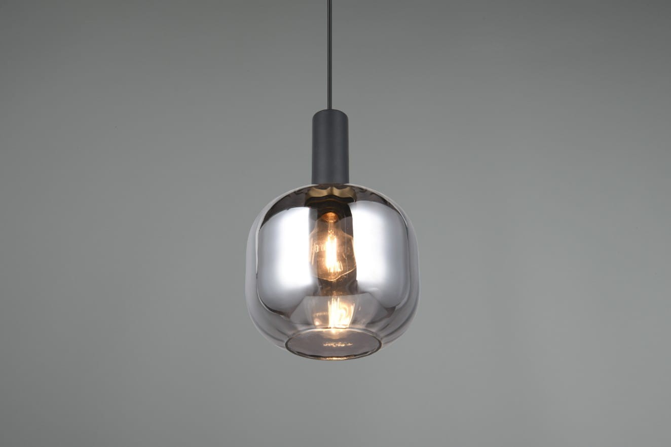 Czarna lampa wisząca Diva z chromowaną szklanką, zawieszona na cienkim kablu. Kształt kulisty, z widoczną żarówką E27 w środku. Tło w odcieniu szarości, co podkreśla elegancki wygląd lampy.