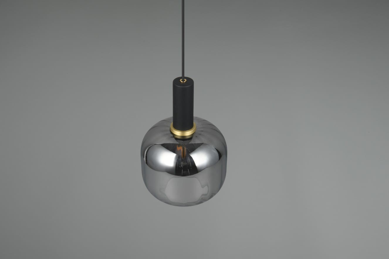 Lampa wisząca Diva z jednym źródłem E27, o kształcie okrągłym. Posiada chromowaną, błyszczącą obudowę oraz czarny uchwyt. Złoty detal wokół gniazda. Zawieszona na cienkim kablu, na szarym tle. Idealna do nowoczesnych wnętrz.