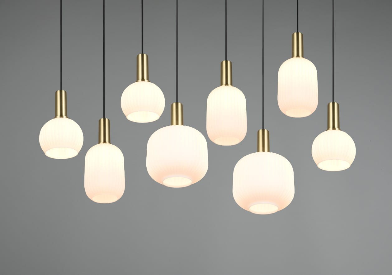 Lampa wisząca Diva z ośmioma kloszami E27 w kształcie cylindrów i kul, w białym kolorze z teksturowaną powierzchnią, zawieszona na czarnych kablach. Metalowe elementy w kolorze złotym. Tło szare, podkreślające elegancję lampy.
