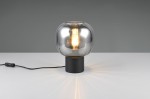 Lampa stołowa Diva z czarnym, okrągłym podstawą i chromowaną, szklaną kopułą. Widoczna żarówka E27 emitująca światło. Kabel z włącznikiem umiejscowiony z boku. Ujęcie frontalne, na jednolitym tle.