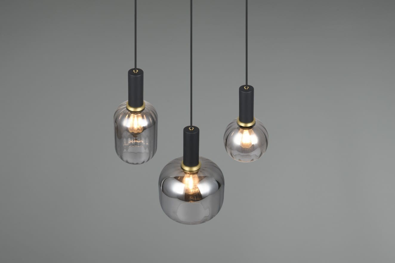 Lampa wisząca Diva w kolorze czarnym i chromowym, z trzema szklanymi kloszami w różnych kształtach. Klosze zawieszone na czarnych linkach, z metalowymi detalami w kolorze złotym. Oświetlenie przeznaczone na trzy żarówki E27.
